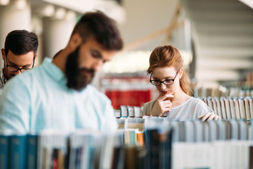 Young attractive students spending time in library