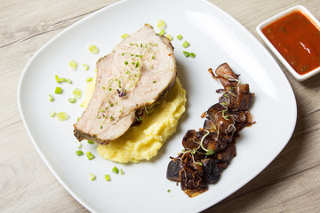 Baked pork with mashed potatoes, fried mushrooms and tomato sauce. Close-up, selective focus.