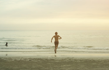 Fototapeta na wymiar Boy running to sea on summer holiday. concept for travel beach
