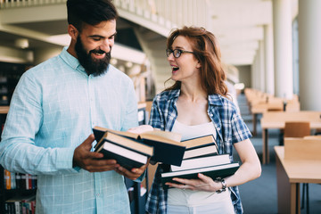 Young attractive students spending time in library