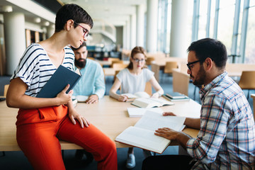 Young attractive students spending time in library