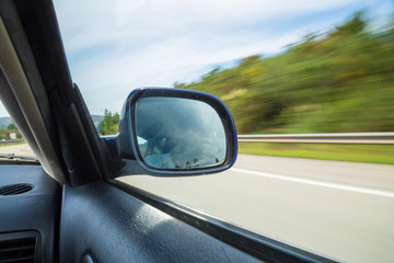Fototapeta na wymiar Rearview mirror of a car driving on a mountain road. 