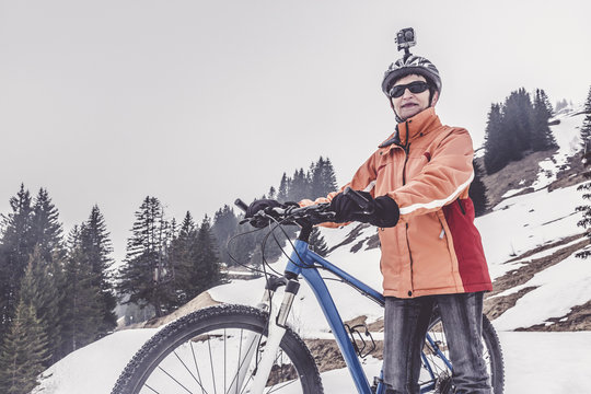 Austria, Damuels, woman with mountain bike and action cam in winter landscape
