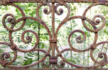 Close up of a rusty railing with green leafs in background