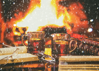 Two glasses of hot drink wine, antique books, fireplace