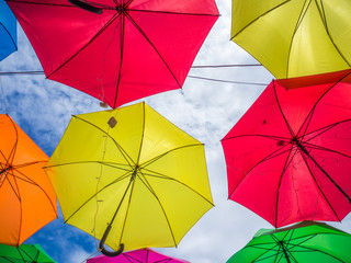Multicolored umbrella pattern decorated with cloudy sky background.