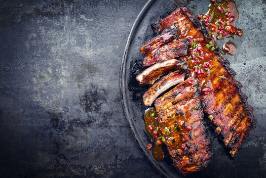 Barbecue pork spare ribs with fruit relish as top view on an old rustic board with copy space