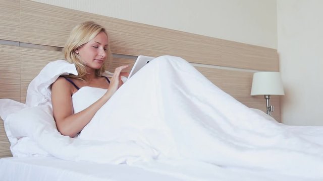 Woman using digital tablet computer and laying on bed