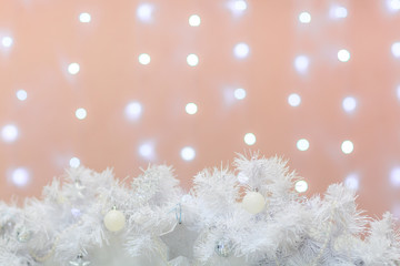 White christmas decoration with lights on the orange background. Free space for the text.