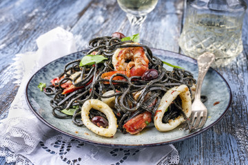 Italian linguine con tinta de calamari and prawns with olives as close-up on a plate