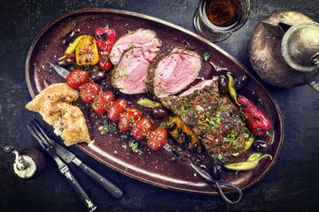 Barbecue Lamb Roast with skewered tomatoes and olives as close-up on a plate
