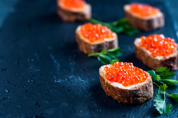 Red caviar on slate background.