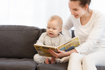 Pretty young mother reading a book to her little baby boy. Family holiday and togetherness.