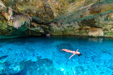 Fototapeta premium Cenote Dos Ojos in Quintana Roo, Mexico. People swimming and snorkeling in clear blue water. This cenote is located close to Tulum in Yucatan peninsula, Mexico.
