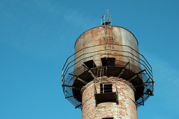 Old and rusty water tower on a background of blue clear sky