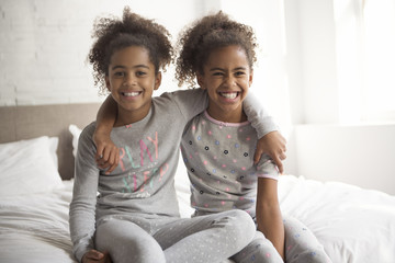 Two little african american girls on bed at home