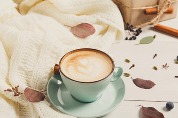 Autumn cappuccino coffee cup on white wood background