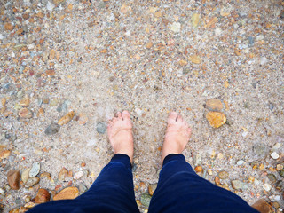 Feet on the beach with sea water and rock 