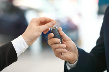 Fototapeta premium Close-up image of the car salesman hand giving a key to new owner