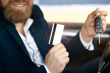 Cropped image of happy male buyer with a credit card in his hand. Focus on a credit card.