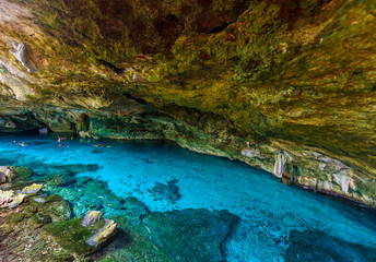 Cenote Dos Ojos in Quintana Roo, Mexico. People swimming and snorkeling in clear blue water. This cenote is located close to Tulum in Yucatan peninsula, Mexico.