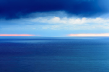 Obraz premium Stylized abstract landscape seascape sunset long exposure with clouds under different shades of blue, orange, yellow and red.