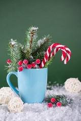 Christmas or new year card . Cup with fir trees and candy canes . On green bright background.