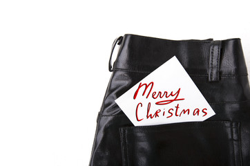 Naklejka premium Merry Christmas on white paper in the pocket of leather trousers