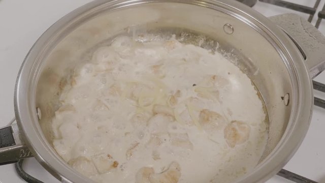 Top view of adding cheese to the pan with the chicken. Chicken frying in a pan. Closeup of chicken meat cooking on a hot pan on a gas stove