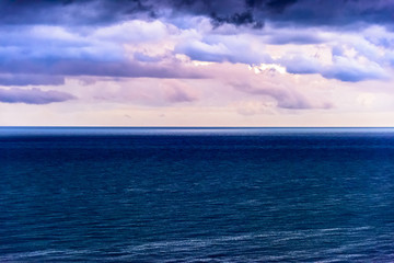 Obraz premium Stylized abstract landscape seascape sunset long exposure with clouds under different shades of blue, orange, yellow and red.