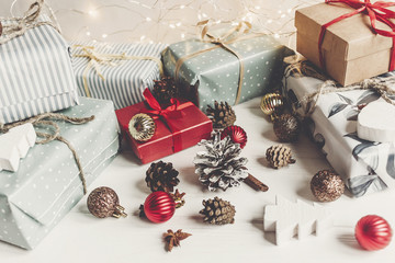 merry christmas concept. present boxes with ornaments tree cones anise and lights on the rustic white wooden background, space for text. seasonal greetings. happy holidays