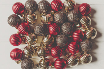 christmas flat lay. red and gold christmas ornaments on white wooden background top view. seasonal greetings card. happy holidays. blurred defocused image.