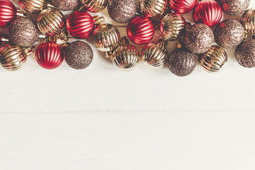 christmas flat lay. red and gold christmas ornaments  frame or border on white wooden background top view with space for text. seasonal greetings card. happy holidays