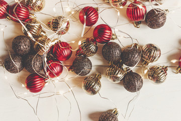 christmas ornaments in red and gold colors with illumination lights on white wooden background top view with space for text. seasonal greetings card. happy holidays. merry xmas