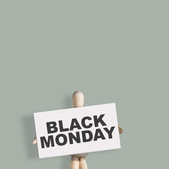 Wooden mannequin hold board with text Black Monday on green background