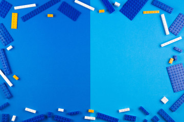 Toys background. Blue, white and yellow plastic construction blocks on blue background