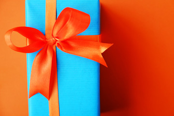 Wrapped present box on orange bright background. Holiday concept. 