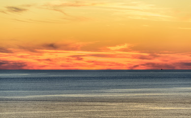 Obraz premium Stylized abstract landscape seascape sunset long exposure with clouds under different shades of blue, orange, yellow and red.