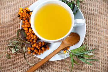 Tea made from sea buckthorn berries healthy for health delicious, saturated with vitamins surrounded by berries and sea buckthorn leaves and maintaining health in the body top view