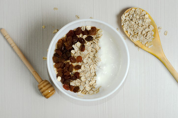 Oatmeal with raisins and yogurt. Oatmeal in the wooden spoon. Flat top view