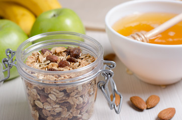 Healthy food. Fruit, homemade granola, nuts, honey on a white table
