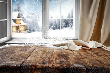 Wooden table with space for your product. Curtain in the window. Open window with snowflakes. Landscape of winter forest. Morning sunshine. © magdal3na