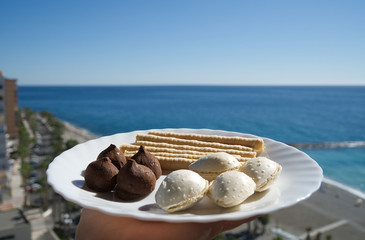Spanish traditional dessert called "almendras rellenas" with sea and beach at the background.