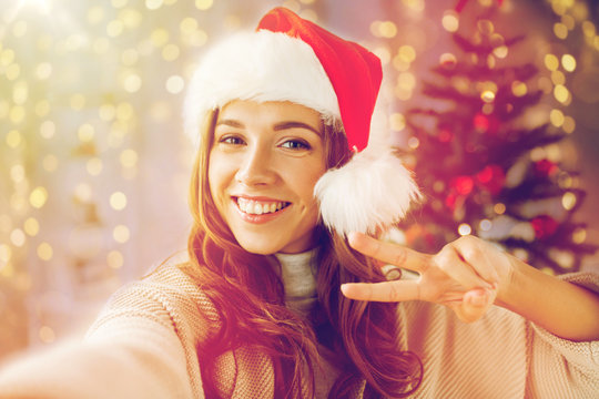 happy woman taking selfie over christmas tree