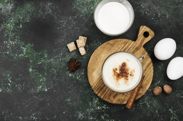 Christmas drink eggnog and ingredients on a green background. Top view, copy space