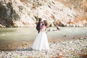 Fototapeta na wymiar Wedding couple, groom and bride hugging, outdoor near river