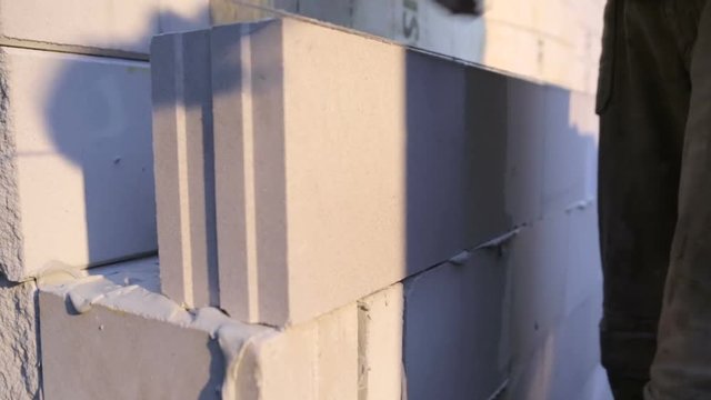 Worker placing a cement block on a wall