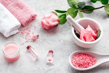 Make cosmetics with rose  oil. Mortar with rose petals and pestle on grey background