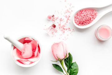 Make cosmetics with rose  oil. Mortar with rose petals and pestle on white background top view copyspace