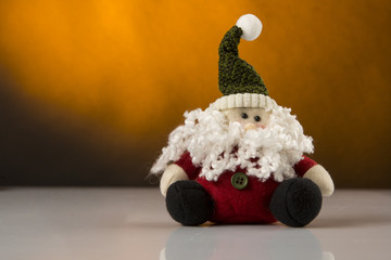 Pupazzo di Babbo Natale sopra superficie bianca riflettente - sfondo colore senape